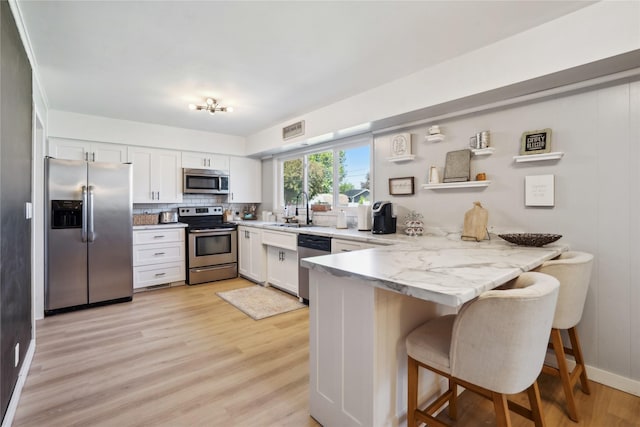 743 15th St, Nevada, IA 50201 - kitchen with stainless steel appliances, a peninsula, a sink, light wood-type flooring, and white cabinets