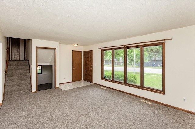 7405 Aurora Ave, Urbandale, IA 50322 - unfurnished living room featuring carpet floors, stairway, and baseboards