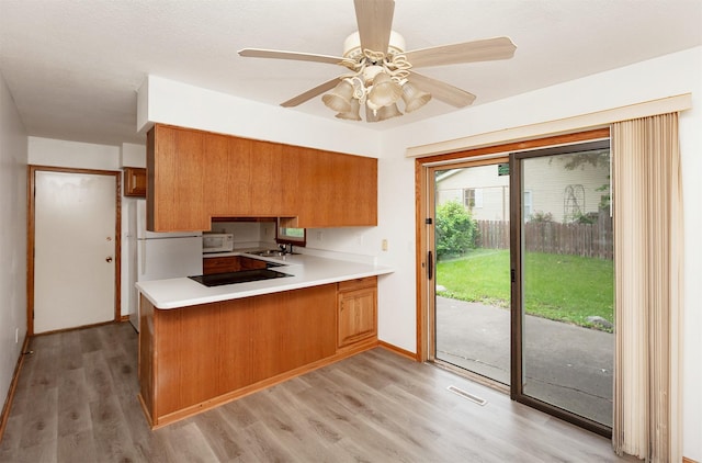 7405 Aurora Ave, Urbandale, IA 50322 - kitchen featuring brown cabinets, white appliances, a peninsula, and light countertops