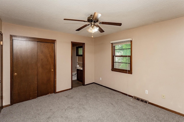 7405 Aurora Ave, Urbandale, IA 50322 - unfurnished bedroom featuring light carpet, baseboards, a closet, ensuite bathroom, and a textured ceiling