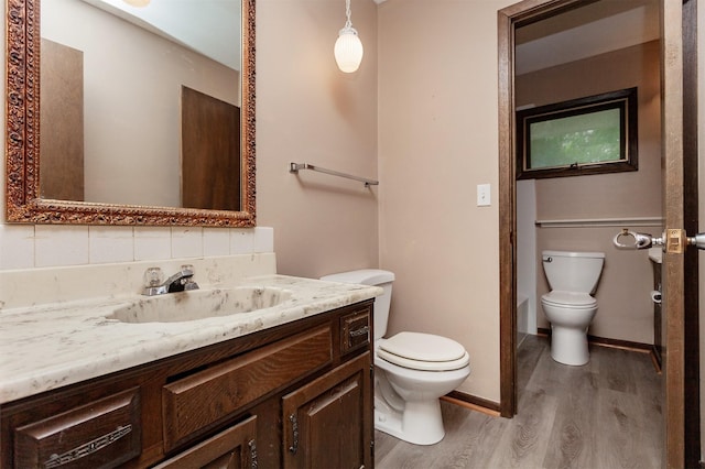 7405 Aurora Ave, Urbandale, IA 50322 - bathroom featuring toilet, wood finished floors, vanity, and baseboards