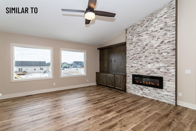 532 Wicker Dr, Huxley, IA 50124 - unfurnished living room with a stone fireplace, wood finished floors, a ceiling fan, lofted ceiling, and baseboards