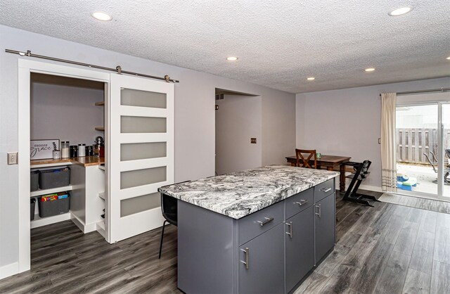 405 Joy Cir, Gilbert, IA 50105 - kitchen featuring dark wood finished floors, a textured ceiling, recessed lighting, a kitchen island, and a barn door