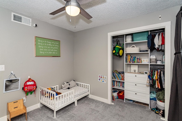 405 Joy Cir, Gilbert, IA 50105 - carpeted bedroom with a crib, a closet, a textured ceiling, baseboards, and ceiling fan