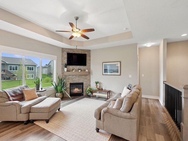 8876 Scarlet Dr, West Des Moines, IA 50266 - living area featuring a ceiling fan, wood finished floors, a raised ceiling, a fireplace, and baseboards