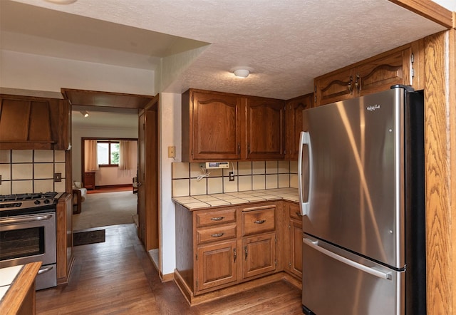 203 11th St, Dallas Center, IA 50063 - kitchen with stainless steel appliances, tile counters, tasteful backsplash, wood finished floors, and a textured ceiling