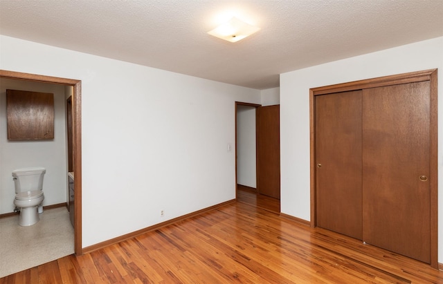 203 11th St, Dallas Center, IA 50063 - unfurnished bedroom featuring a closet, baseboards, light wood-type flooring, and ensuite bath
