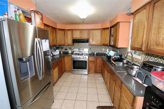 1929 10th St, Des Moines, IA 50314 - kitchen featuring appliances with stainless steel finishes, range hood, a sink, brown cabinetry, and a textured ceiling
