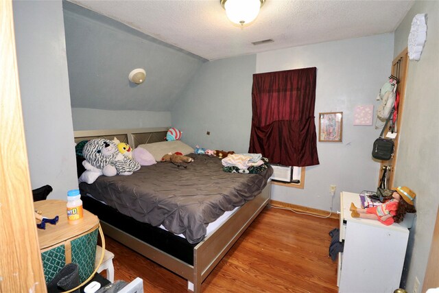 1929 10th St, Des Moines, IA 50314 - bedroom with wood finished floors, vaulted ceiling, and a textured ceiling