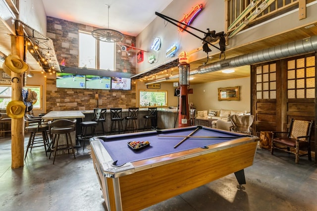 105 S Shore Dr, Montezuma, IA 50171 - playroom with concrete flooring, a high ceiling, pool table, and bar area