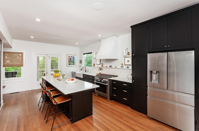 2606 Forest Dr, Des Moines, IA 50312 - kitchen featuring stainless steel appliances, dark cabinets, light wood finished floors, a breakfast bar area, and recessed lighting