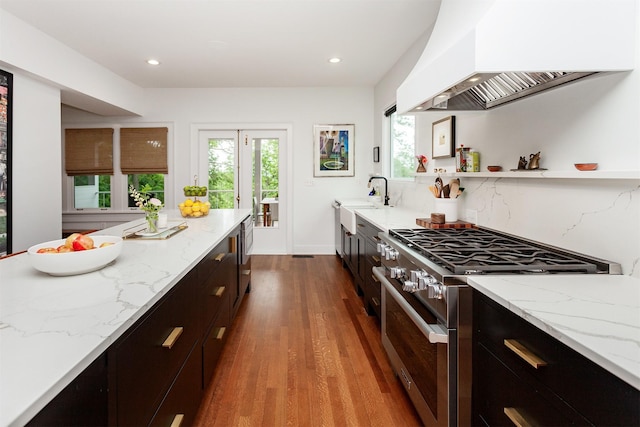 2606 Forest Dr, Des Moines, IA 50312 - kitchen featuring high end stove, custom exhaust hood, wood finished floors, light stone countertops, and dark cabinetry