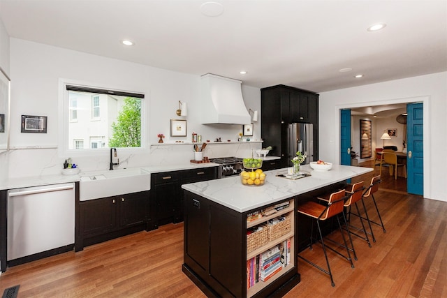 2606 Forest Dr, Des Moines, IA 50312 - kitchen with stainless steel appliances, custom exhaust hood, open shelves, a breakfast bar, and dark cabinetry