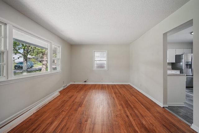 2407 E Tiffin Ave, Des Moines, IA 50317 - spare room featuring wood finished floors, a textured ceiling, and baseboards