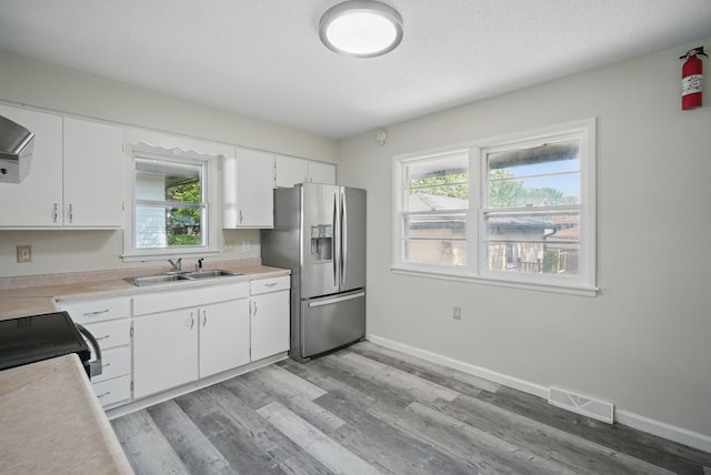 2407 E Tiffin Ave, Des Moines, IA 50317 - kitchen with stainless steel fridge with ice dispenser, a sink, light countertops, and white cabinets