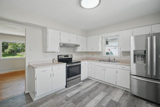 2407 E Tiffin Ave, Des Moines, IA 50317 - kitchen with stainless steel appliances, under cabinet range hood, a sink, light countertops, and baseboards