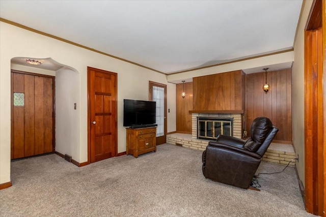 862 40th Pl, Des Moines, IA 50312 - living room with crown molding, light colored carpet, a fireplace, baseboards, and wooden walls