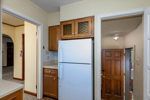 862 40th Pl, Des Moines, IA 50312 - kitchen with freestanding refrigerator, arched walkways, brown cabinets, and light countertops