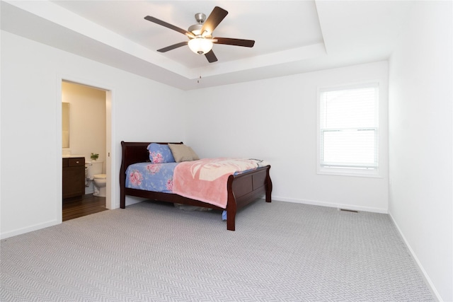 2357 Shadow Creek Cir, Des Moines, IA 50320 - carpeted bedroom with a tray ceiling, ensuite bathroom, baseboards, and a ceiling fan