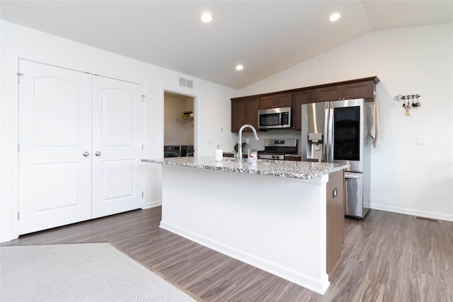 2357 Shadow Creek Cir, Des Moines, IA 50320 - kitchen with stainless steel appliances, dark brown cabinets, lofted ceiling, an island with sink, and dark wood-style floors