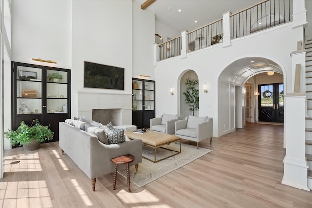 3834 NW 177th Ct, Clive, IA 50325 - living area featuring arched walkways, a high ceiling, wood finished floors, a fireplace, and french doors