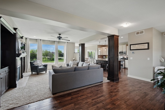 9012 NW 72nd Pl, Johnston, IA 50131 - living area featuring wood-type flooring, a ceiling fan, ornate columns, and baseboards