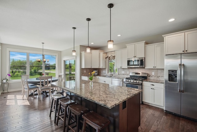 9012 NW 72nd Pl, Johnston, IA 50131 - kitchen with stainless steel appliances, dark wood finished floors, tasteful backsplash, a kitchen island, and recessed lighting