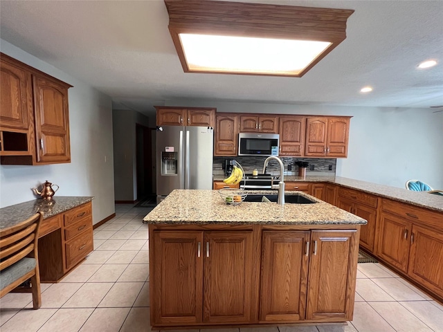210 E 24th St N, Newton, IA 50208 - kitchen with appliances with stainless steel finishes, a sink, light stone countertops, light tile patterned flooring, and brown cabinets