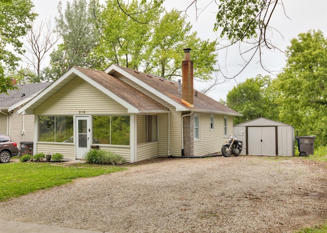 216 56th St, Des Moines, IA 50312 - back of property with a shingled roof, a chimney, gravel driveway, and a lawn