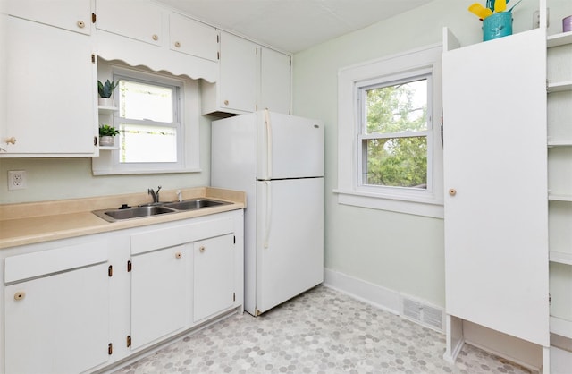 216 56th St, Des Moines, IA 50312 - kitchen featuring a sink, freestanding refrigerator, open shelves, baseboards, and light countertops