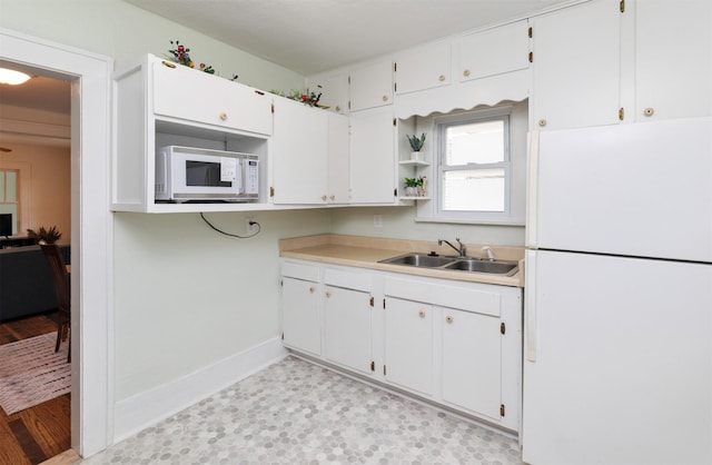 216 56th St, Des Moines, IA 50312 - kitchen with white appliances, a sink, white cabinets, baseboards, and light countertops