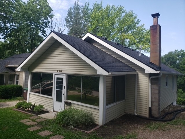 216 56th St, Des Moines, IA 50312 - view of property exterior with a chimney, a shingled roof, and a sunroom