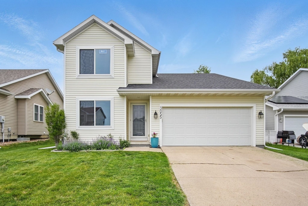 3055 E 52nd St, Des Moines, IA 50317 - traditional-style house with concrete driveway, a front lawn, and a garage