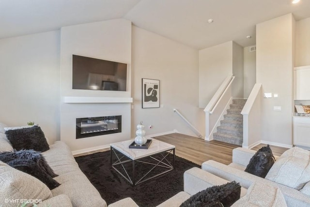14225 Walnut Meadows Dr, Urbandale, IA 50323 - living room featuring wood finished floors, a glass covered fireplace, vaulted ceiling, recessed lighting, and baseboards