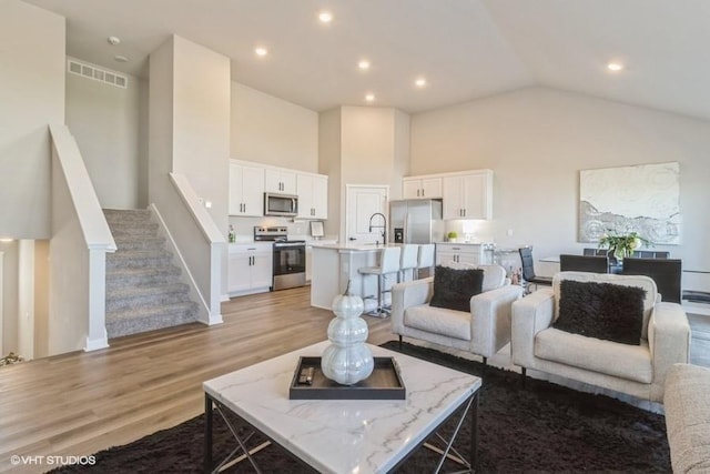 14225 Walnut Meadows Dr, Urbandale, IA 50323 - living area with high vaulted ceiling, light wood finished floors, baseboards, stairway, and recessed lighting