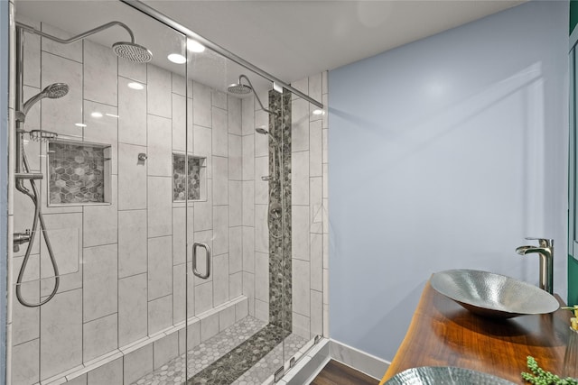 304 11th St SE, Altoona, IA 50009 - bathroom with a shower stall, a sink, baseboards, and wood finished floors