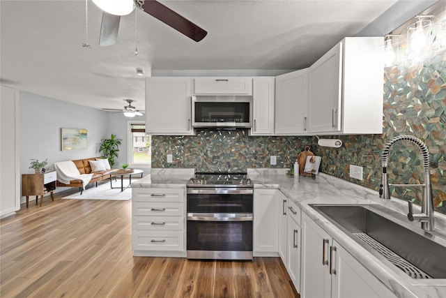 304 11th St SE, Altoona, IA 50009 - kitchen with stainless steel appliances, ceiling fan, a sink, light wood-style flooring, and backsplash