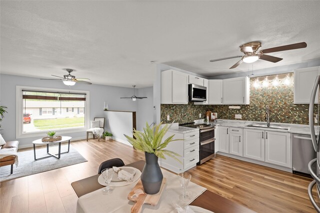 304 11th St SE, Altoona, IA 50009 - kitchen featuring appliances with stainless steel finishes, a sink, ceiling fan, backsplash, and white cabinets