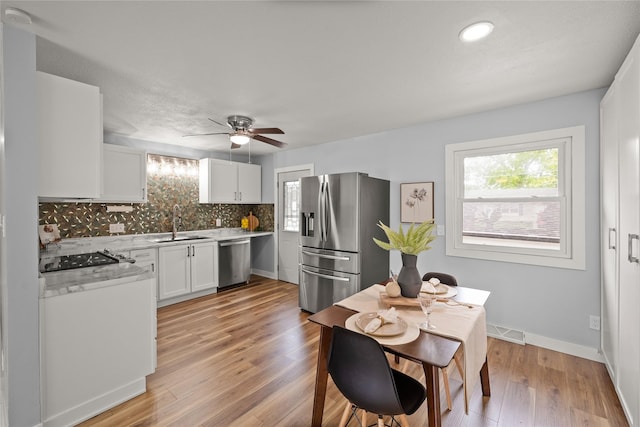 304 11th St SE, Altoona, IA 50009 - kitchen featuring appliances with stainless steel finishes, a sink, white cabinetry, decorative backsplash, and a ceiling fan