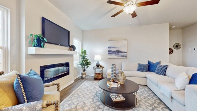 1001 NE 12th St, Grimes, IA 50111 - living room with a ceiling fan, wood finished floors, a glass covered fireplace, and baseboards