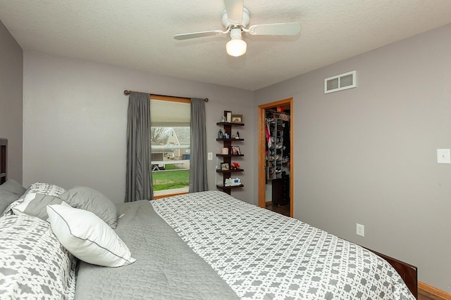 2518 E 39th Ct, Des Moines, IA 50317 - bedroom featuring a walk in closet, a closet, ceiling fan, and a textured ceiling