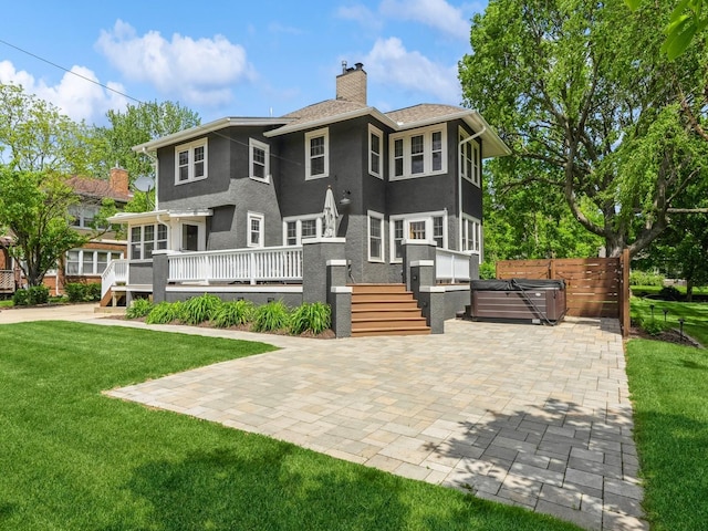 912 45th St, Des Moines, IA 50312 - back of property with stucco siding, a wooden deck, a chimney, a patio area, and a hot tub