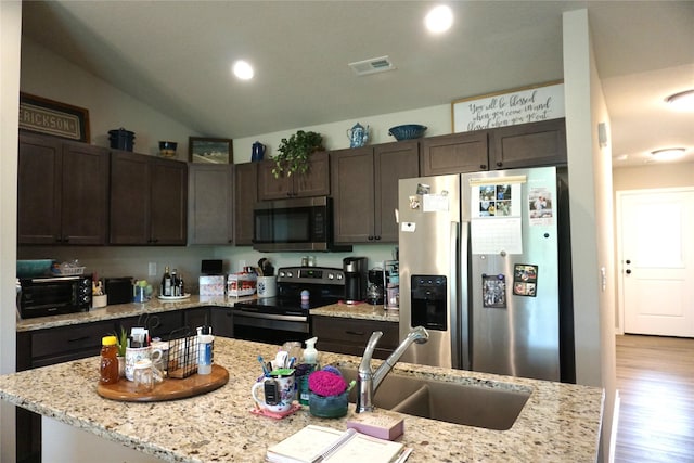 507 W Madison St, Winterset, IA 50273 - kitchen featuring stainless steel appliances, a sink, dark brown cabinets, vaulted ceiling, and wood finished floors