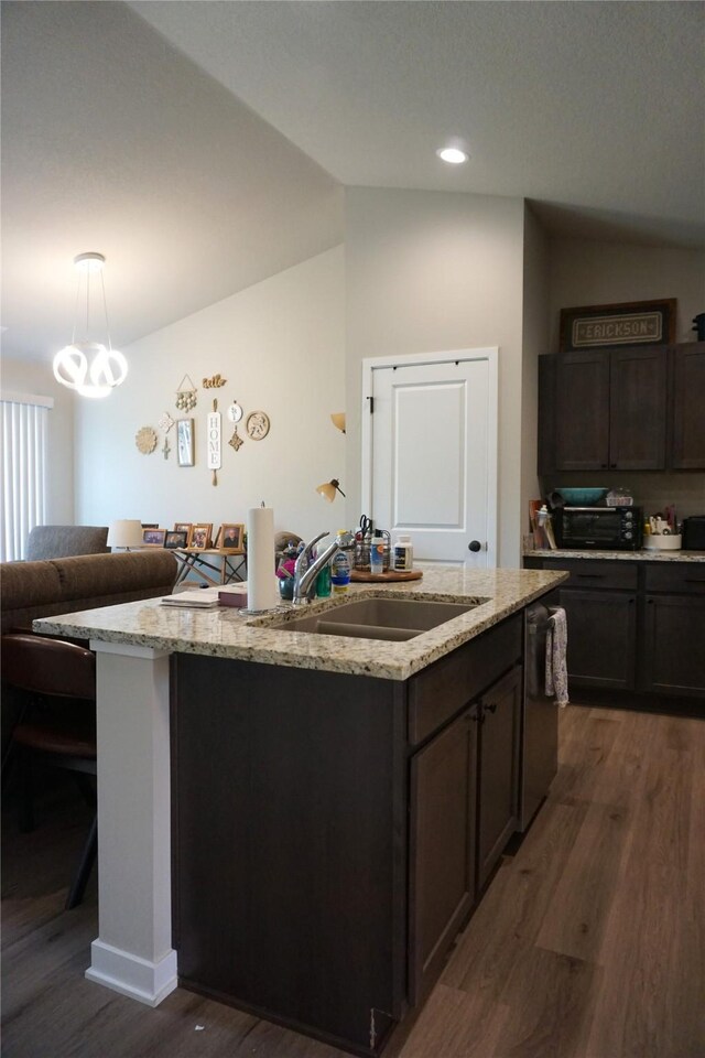 507 W Madison St, Winterset, IA 50273 - kitchen featuring a sink, dark wood finished floors, a center island with sink, light stone countertops, and stainless steel dishwasher