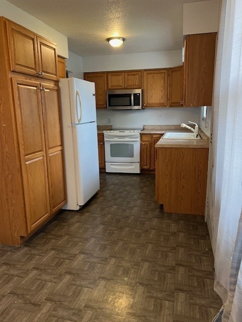 711 SW 2nd St, Stuart, IA 50250 - kitchen featuring white appliances, a sink, brown cabinets, and light countertops