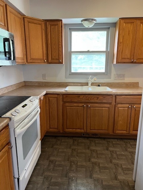 711 SW 2nd St, Stuart, IA 50250 - kitchen with white electric range, a sink, stainless steel microwave, brown cabinetry, and light countertops