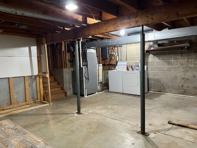 711 SW 2nd St, Stuart, IA 50250 - unfinished basement featuring washing machine and clothes dryer, stairway, heating unit, electric panel, and gas water heater