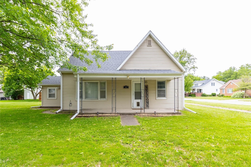 112 N Buchanan St, Monroe, IA 50170 - bungalow featuring a front yard, covered porch, and a shingled roof