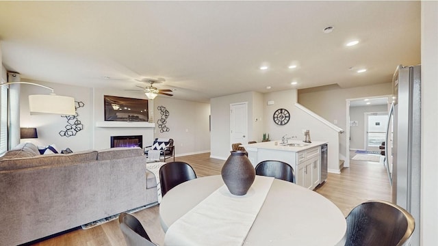 1034 Maple St, Waukee, IA 50263 - dining space with ceiling fan, light wood-style flooring, a glass covered fireplace, recessed lighting, and baseboards