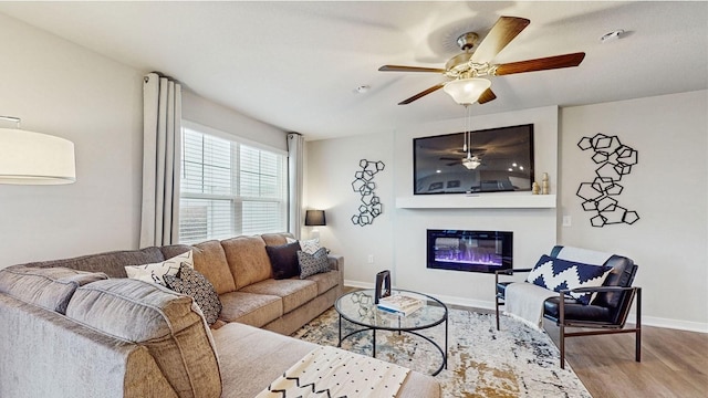 1038 Maple St, Waukee, IA 50263 - living area with wood finished floors, ceiling fan, a glass covered fireplace, and baseboards